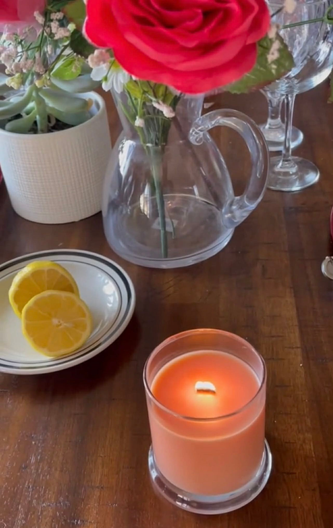 Sweet-scented candle serenely burning in living room with flowers and lemons.