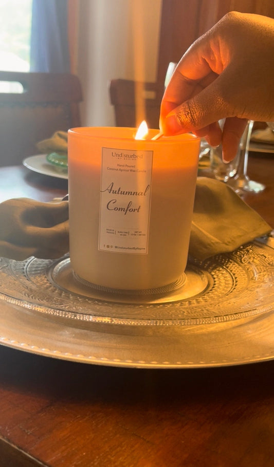 A hand lighting a luxurious scented candle on a kitchen table, creating a warm and inviting atmosphere for holiday gatherings.